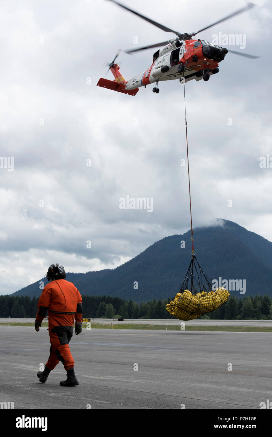 a-coast-guard-air-station-sitka-mh-60-jayhawk-helicopter-crew-hoists-approximately-1300-feet-of-oil-containment-boom-using-cargo-nets-in-juneau-alaska-june-26-2018-the-hoist-was-part-of-an-effort-to-test-and-deploy-oil-containment-boom-across-echo-cove-and-cowee-creek-alaska-as-part-of-a-geographic-response-strategy-listed-in-the-southeast-alaska-area-contingency-plan-us-coast-guard-photo-by-petty-officer-1st-class-jon-paul-rios-P7H1GE.jpg